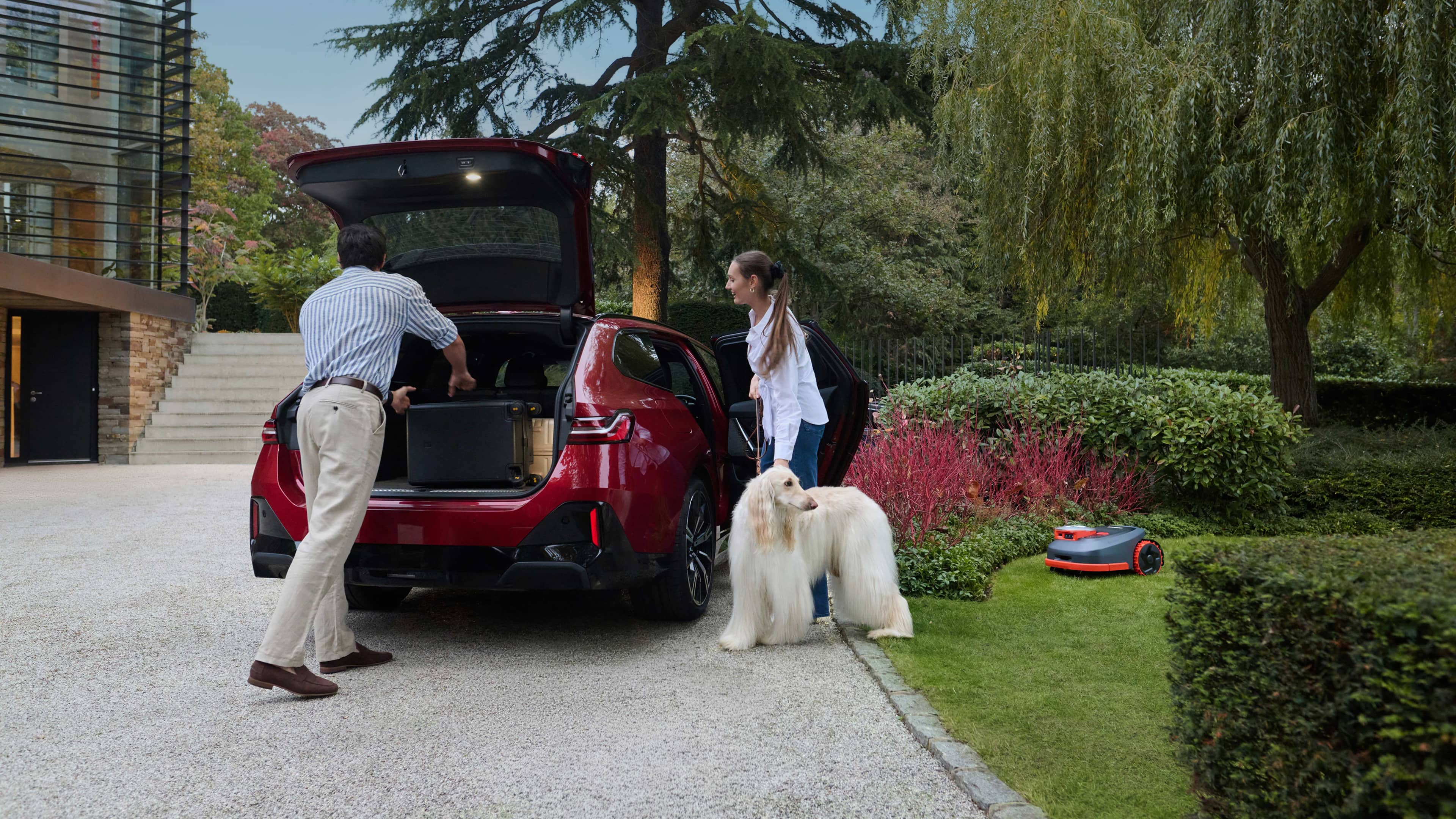 Navimow i110N robot lawn mower mows while family loads car.