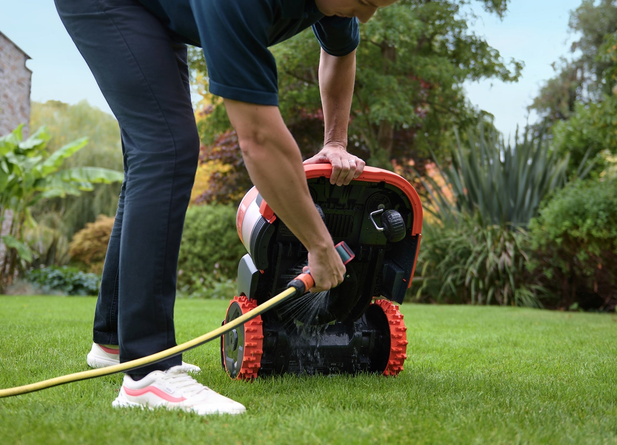 Navimow i105E robot lawn mower being washed with a hose.