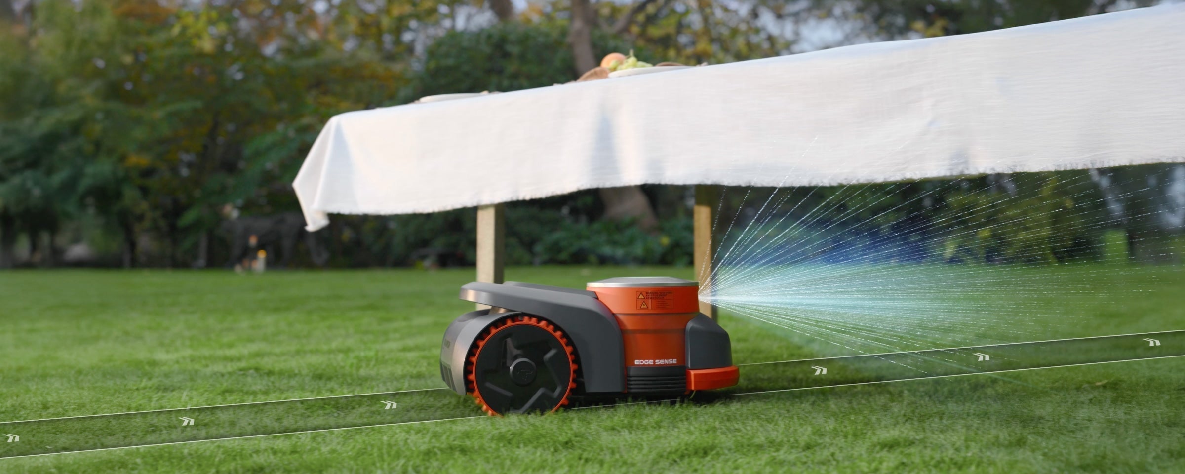 Navimow i105E robot lawn mower mows grass under white table.