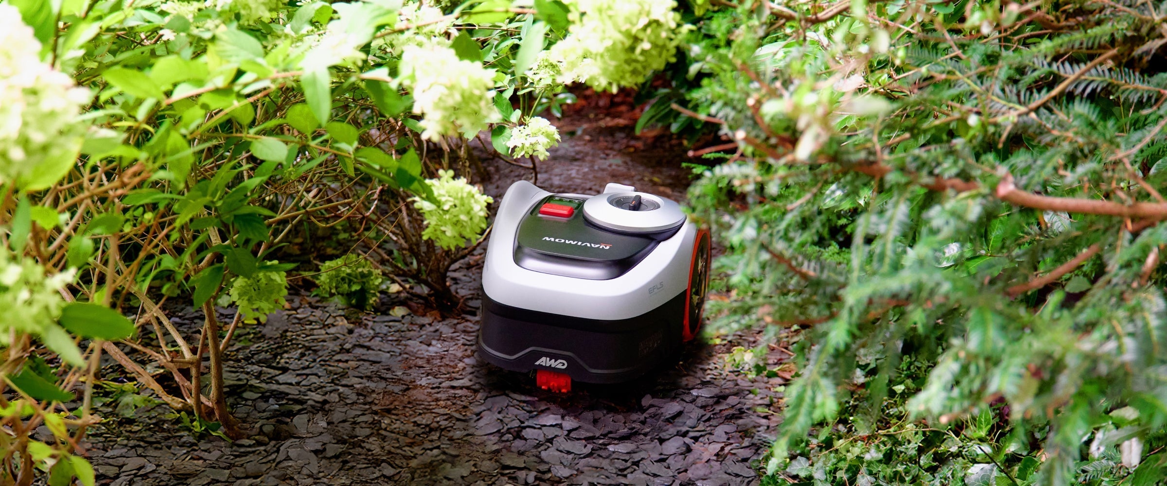 Navimow AWD robot lawn mower on a dark stone path.
