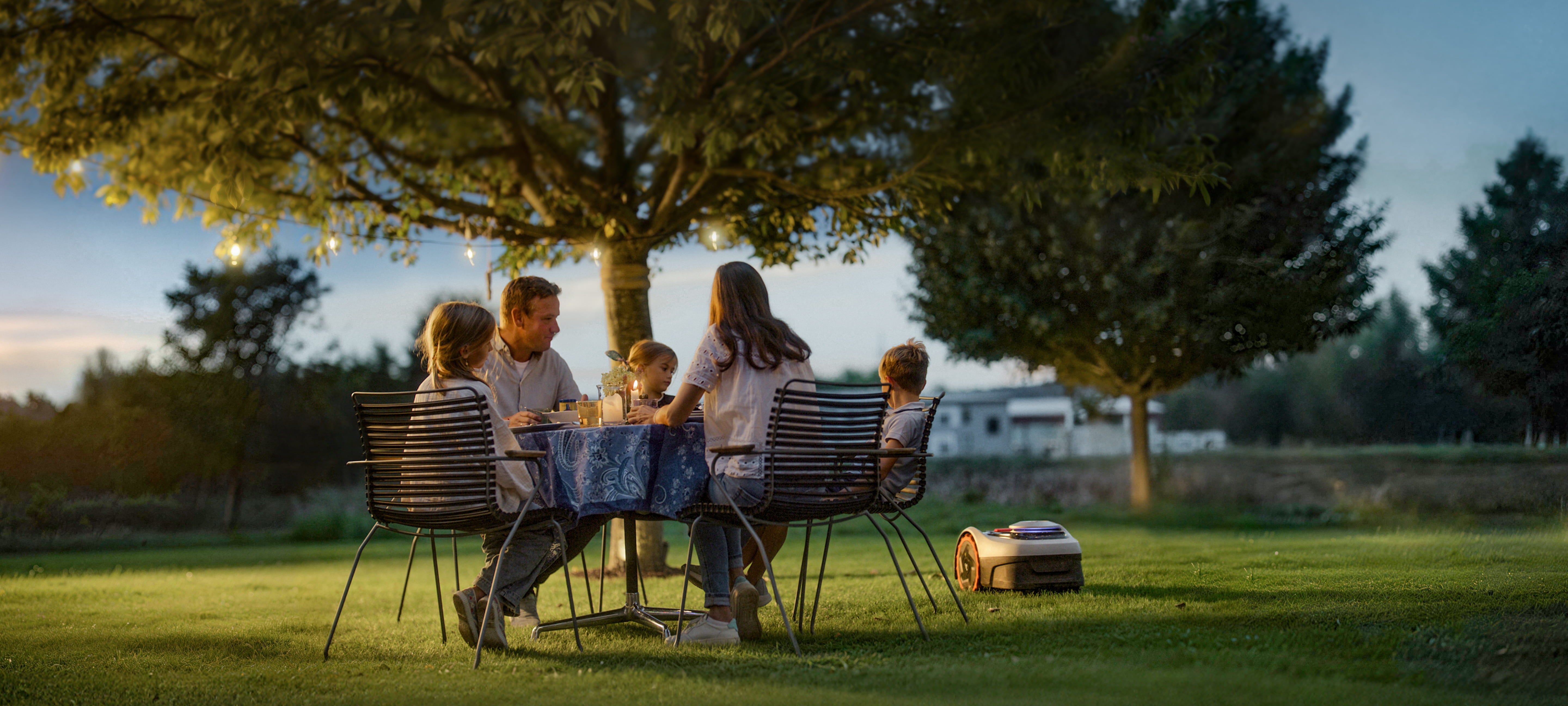 A family having dinner near Navimow i110N robot lawn mower.