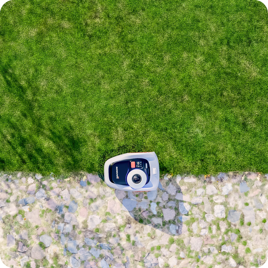 Navimow i110N robot lawn mower stands on a stone path.