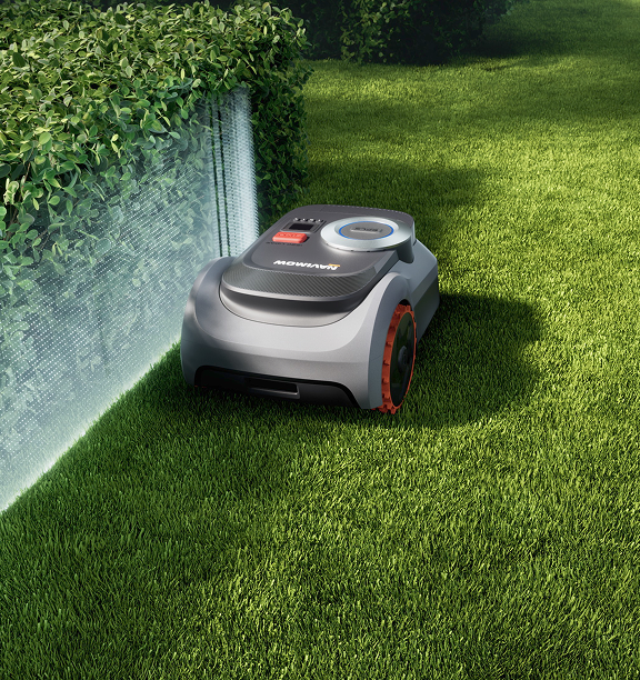 Navimow i110E robot lawn mower mows grass near the hedge.